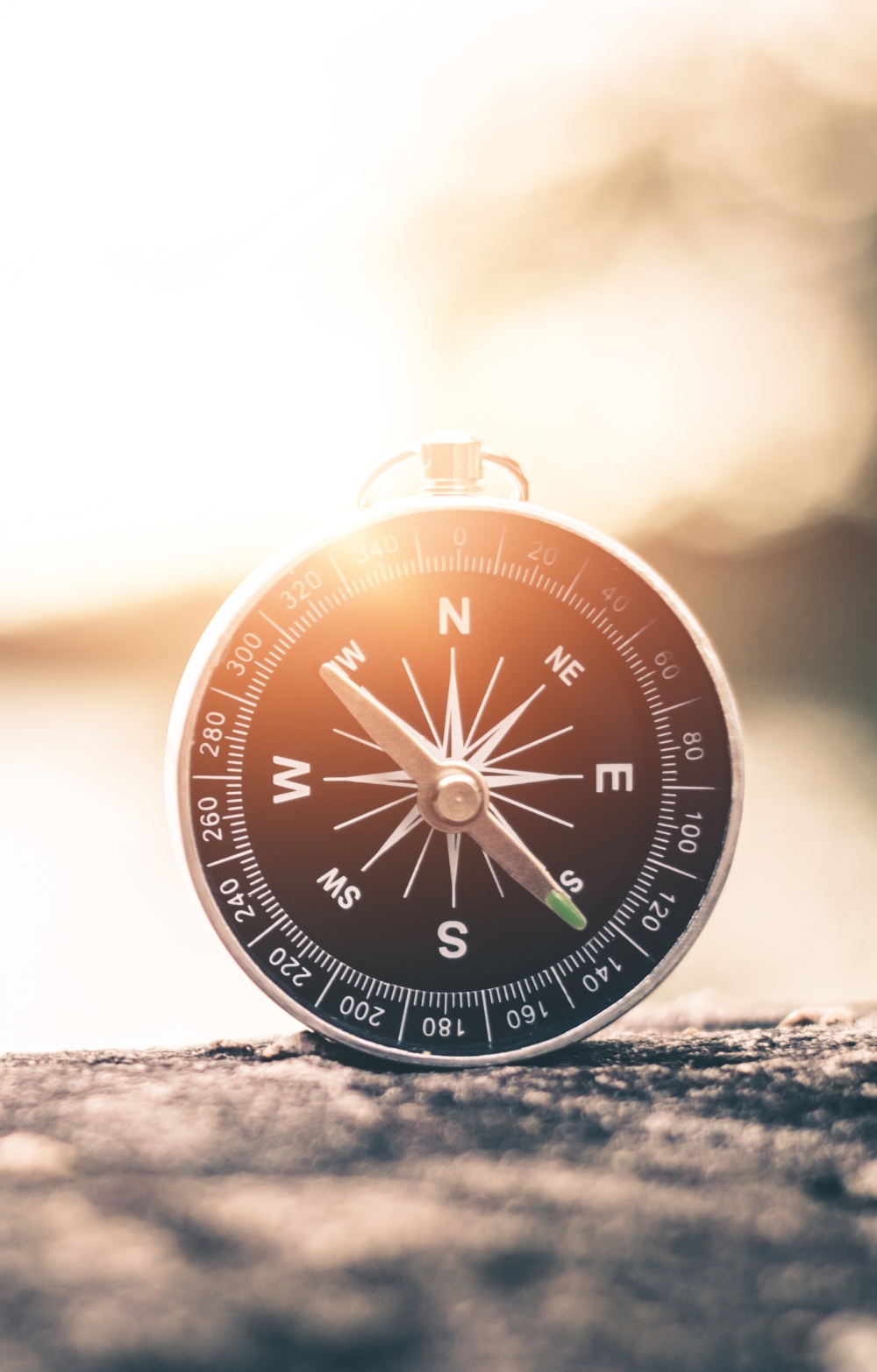 Compass on a pebble against a background of water