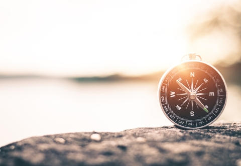 Compass on a pebble against a background of water