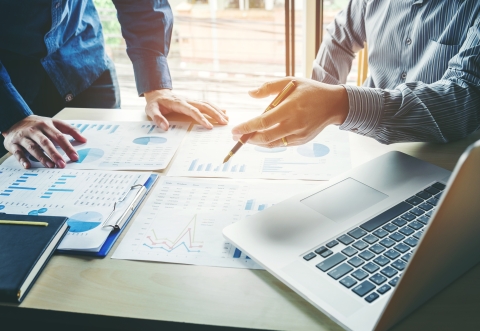 picture of two men talking over a table with documents